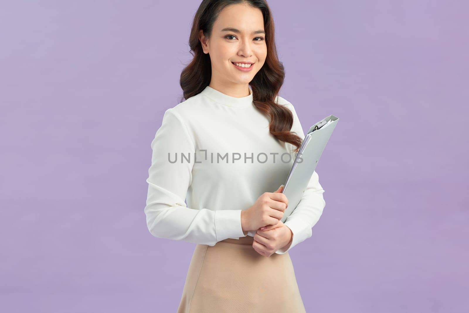Portrait of happy pretty woman standing isolated on violet background, holding clipboard  by makidotvn