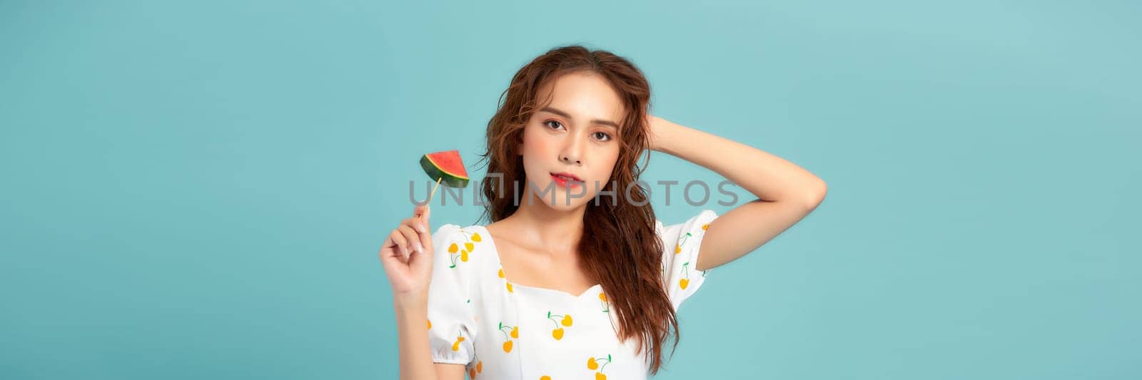 Banner of young woman holding popsicle stick with watermelon isolated on blue