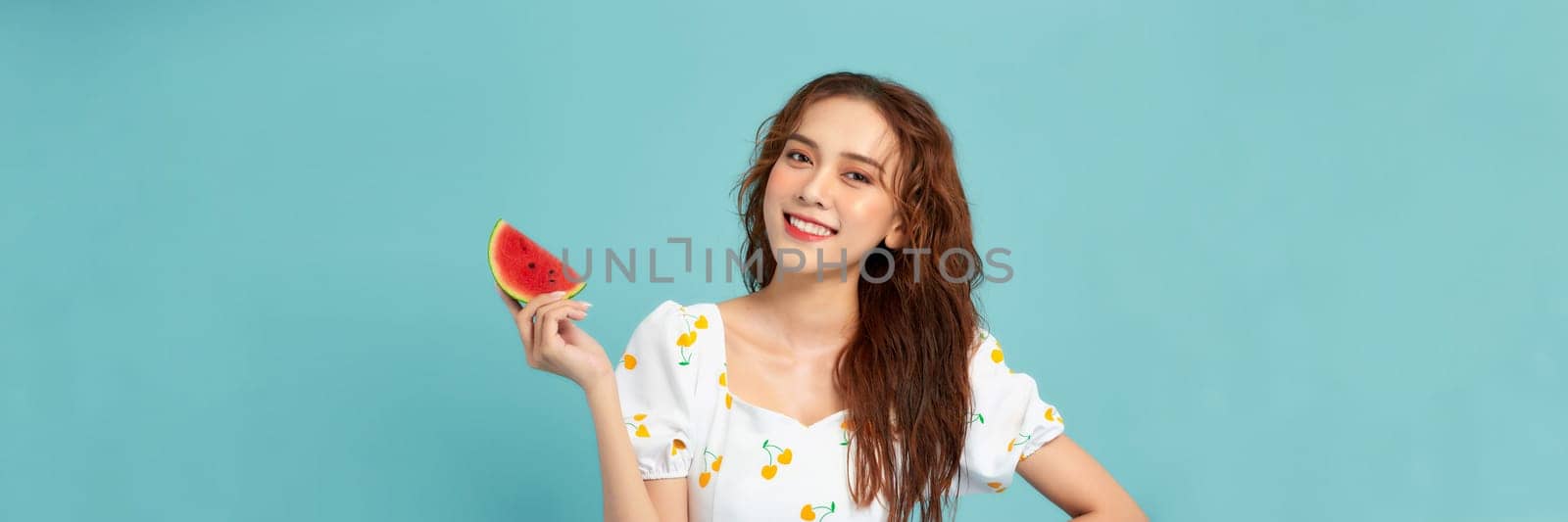 Woman smiling holding and eating slice fresh watermelon on blue background