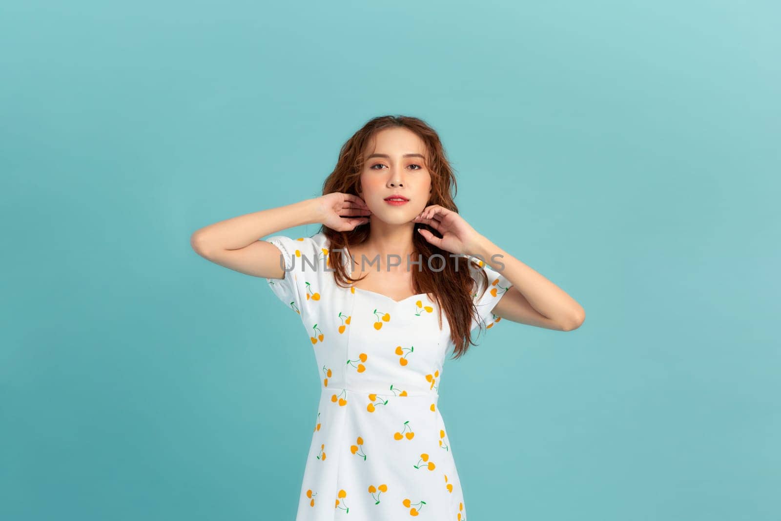 Portrait of a smiling attractive woman in summer dress posing isolated over blue background by makidotvn