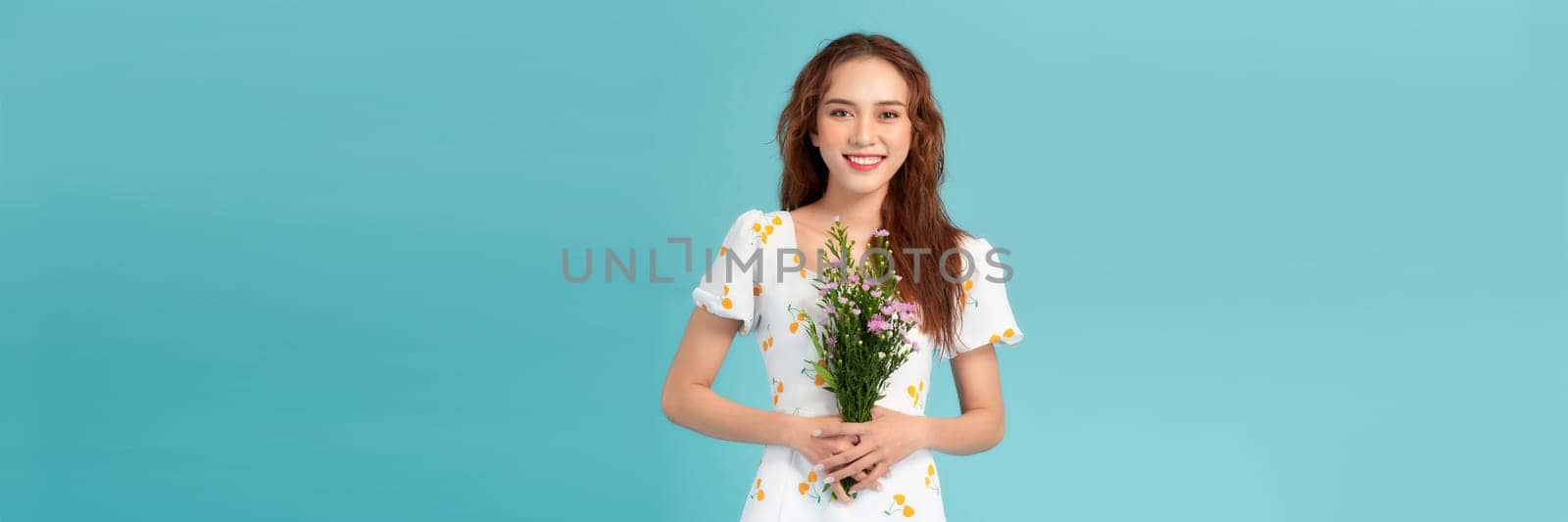 Young beautiful girl with long hair and hat posing with a bouquet of wildflowers. 
