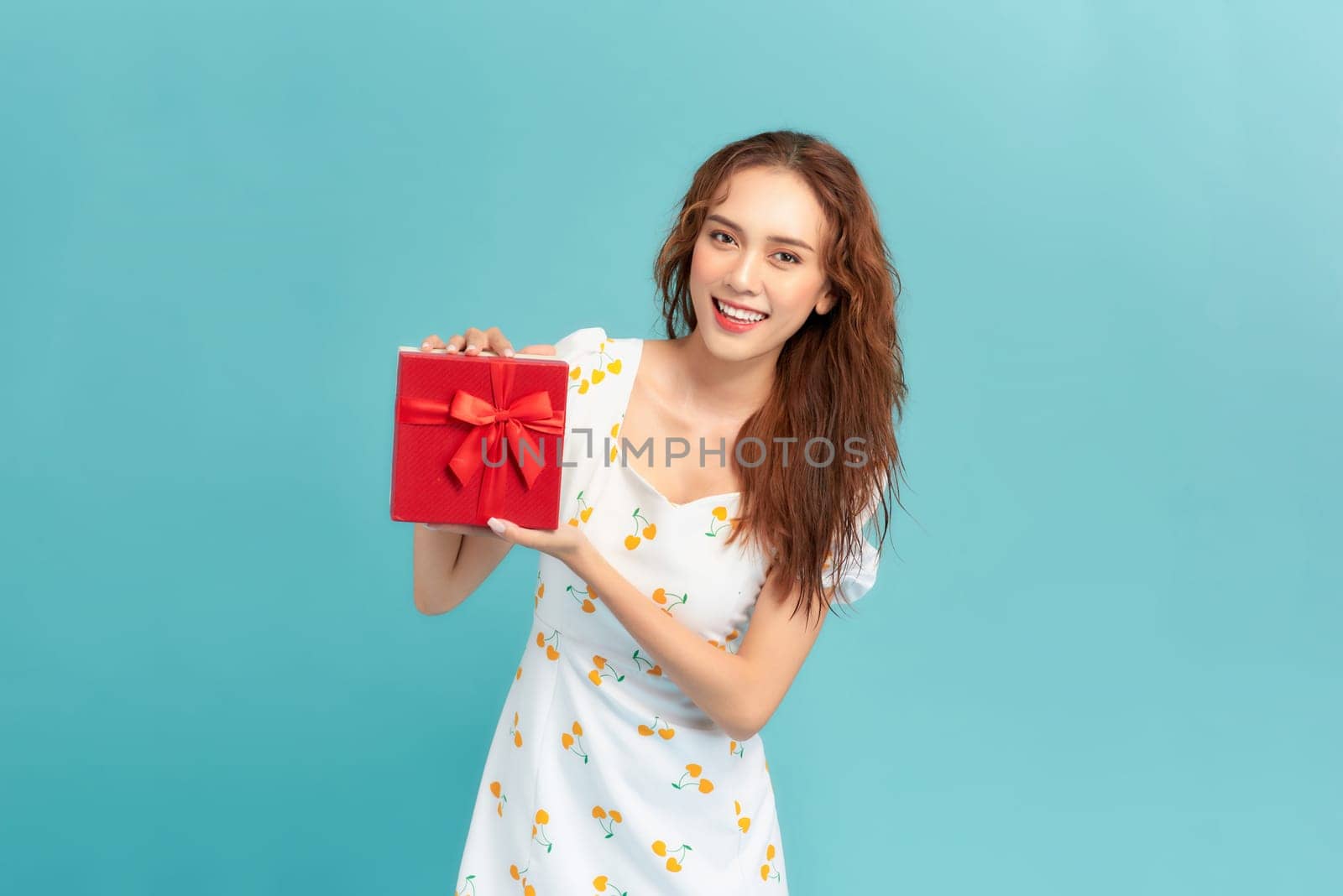 A young happy girl get gift box shake curious present isolated on pastel blue color background by makidotvn