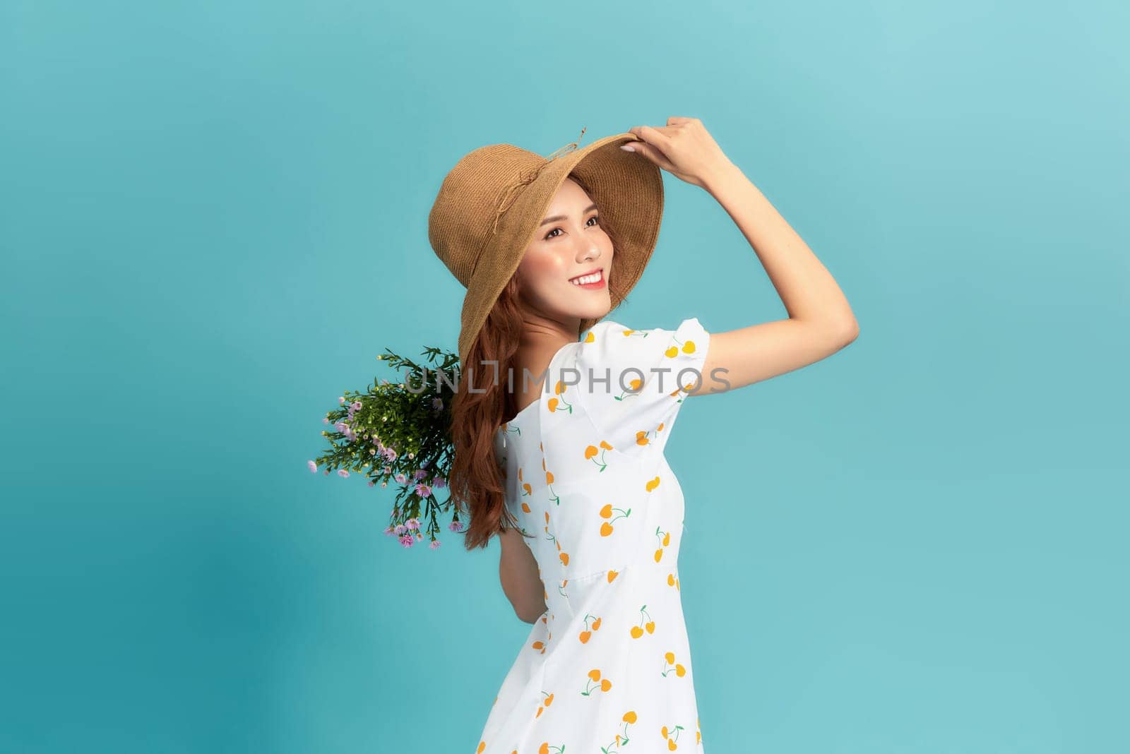 A beautiful young woman in summer dress and straw hat holding wildflowers bouquet by makidotvn