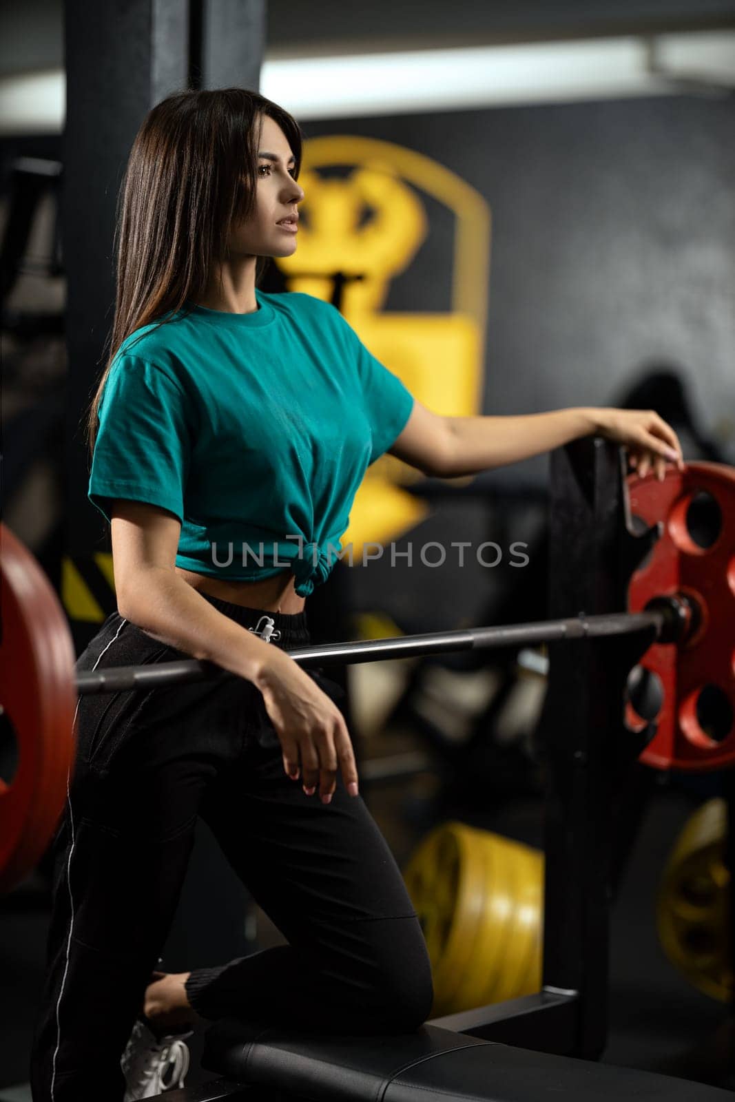 Beautiful athletic girl fitness model leans against bench press bar with weight by but_photo