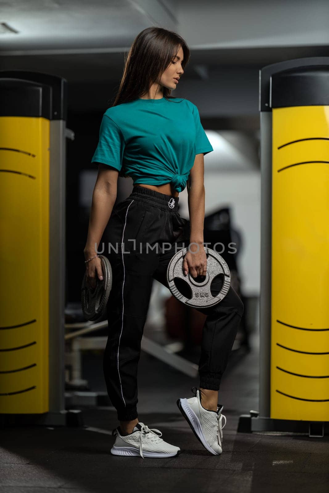 Beautiful sporty girl fitness model posing with weights in the gym by but_photo