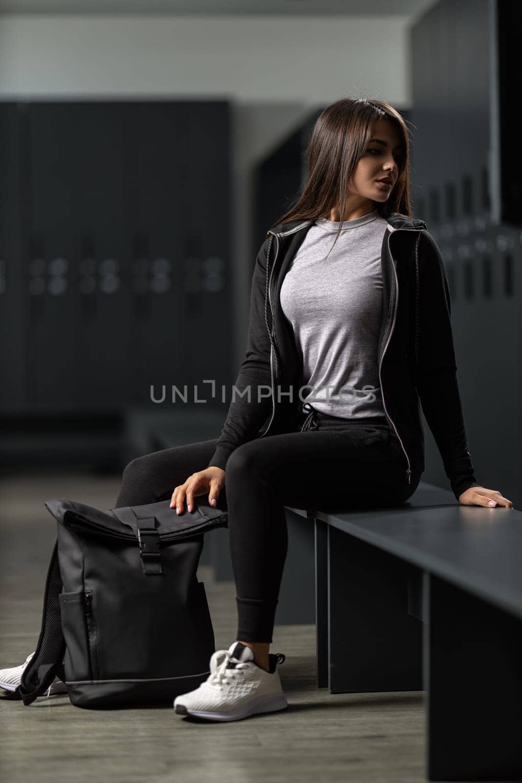Beautiful fit brunette girl in a black tracksuit holding a sports backpack by but_photo