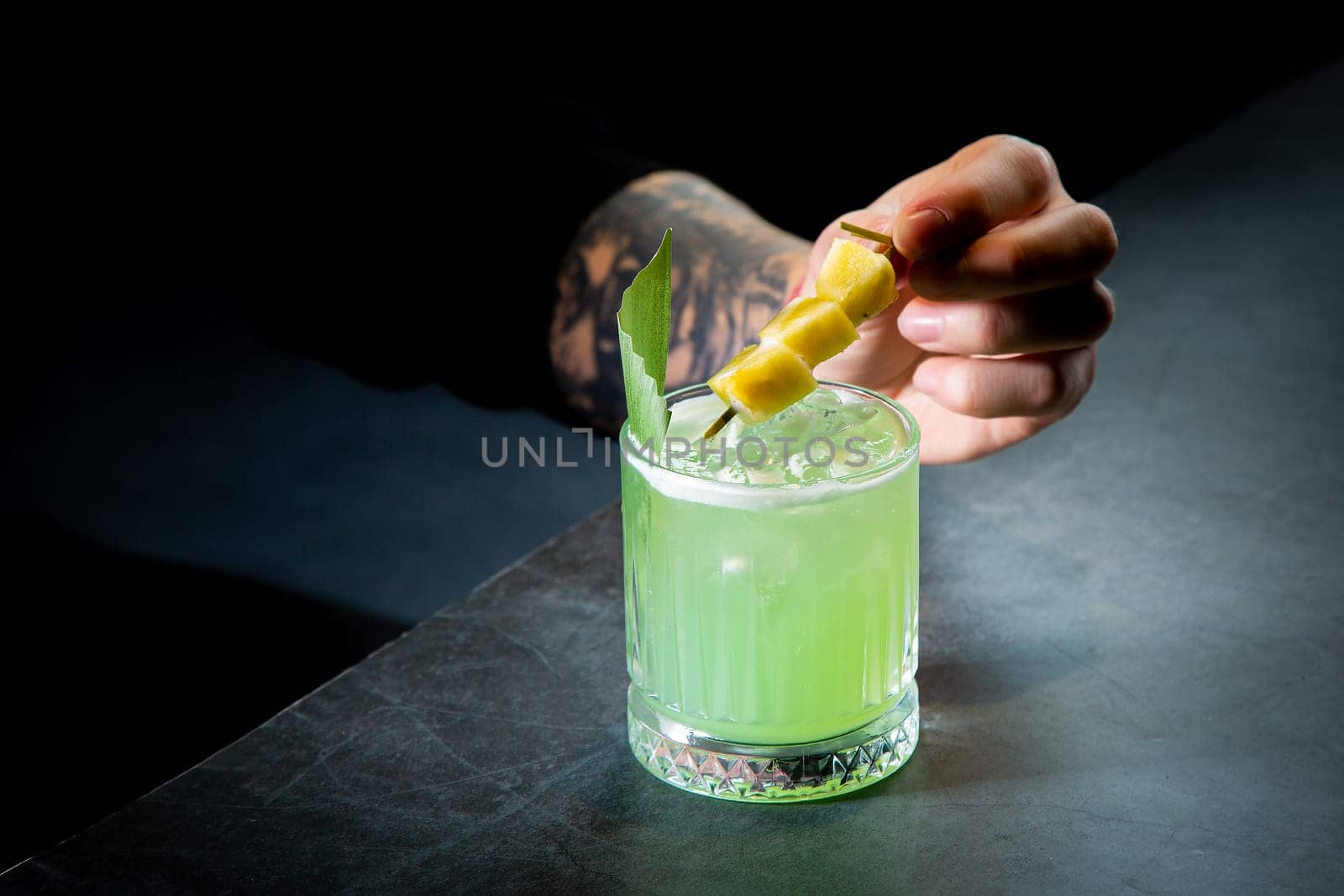 green cocktail with lime in a glass glass with ice and pieces of fruit