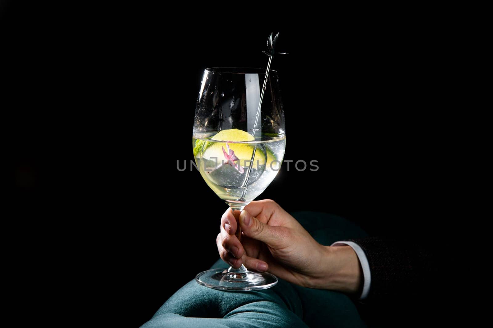 transparent cocktail with ice on a dark background in hand