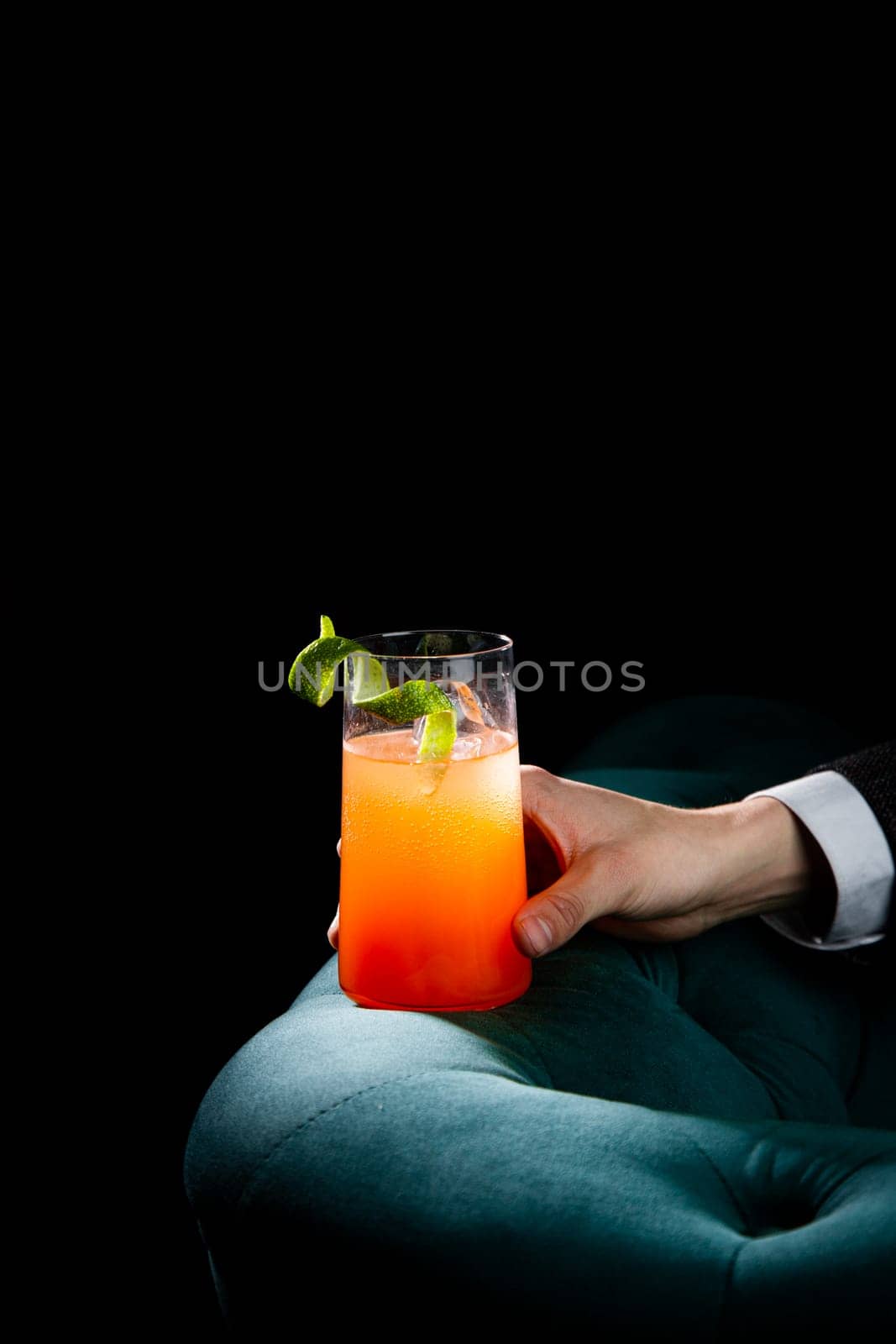 bright tropical cocktail with lime peel and gradient color in a transparent glass, side view by tewolf