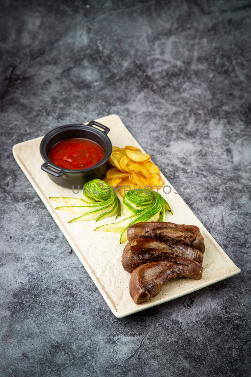 meat ribs with avocado, chips and ketchup on a white plate