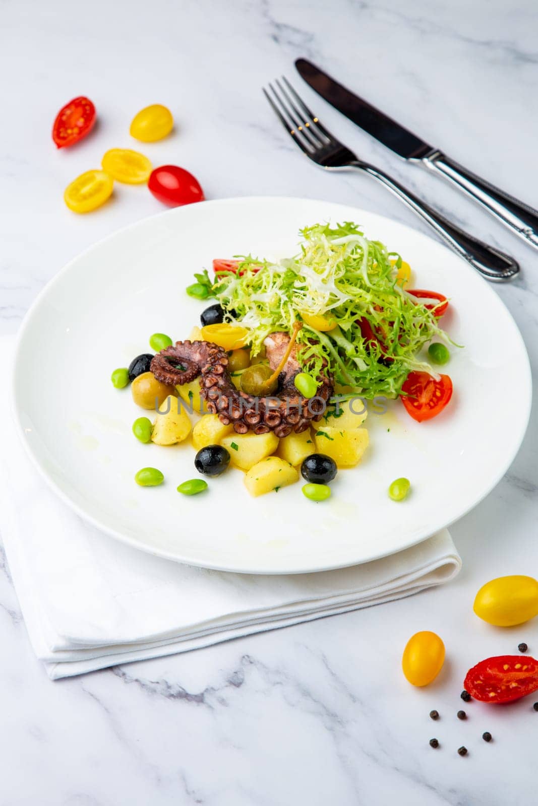 salad with olives, herbs, cherry tomatoes, potatoes and octopus tentacles