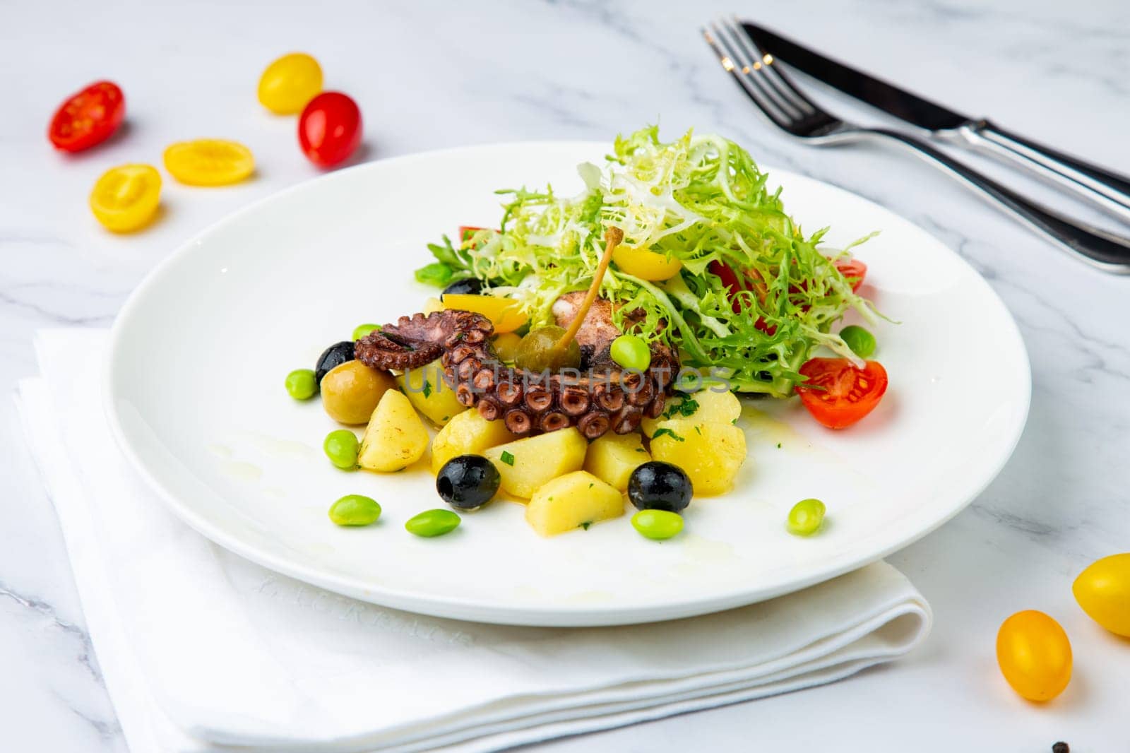 salad with olives, herbs, cherry tomatoes, potatoes and octopus tentacles side view by tewolf
