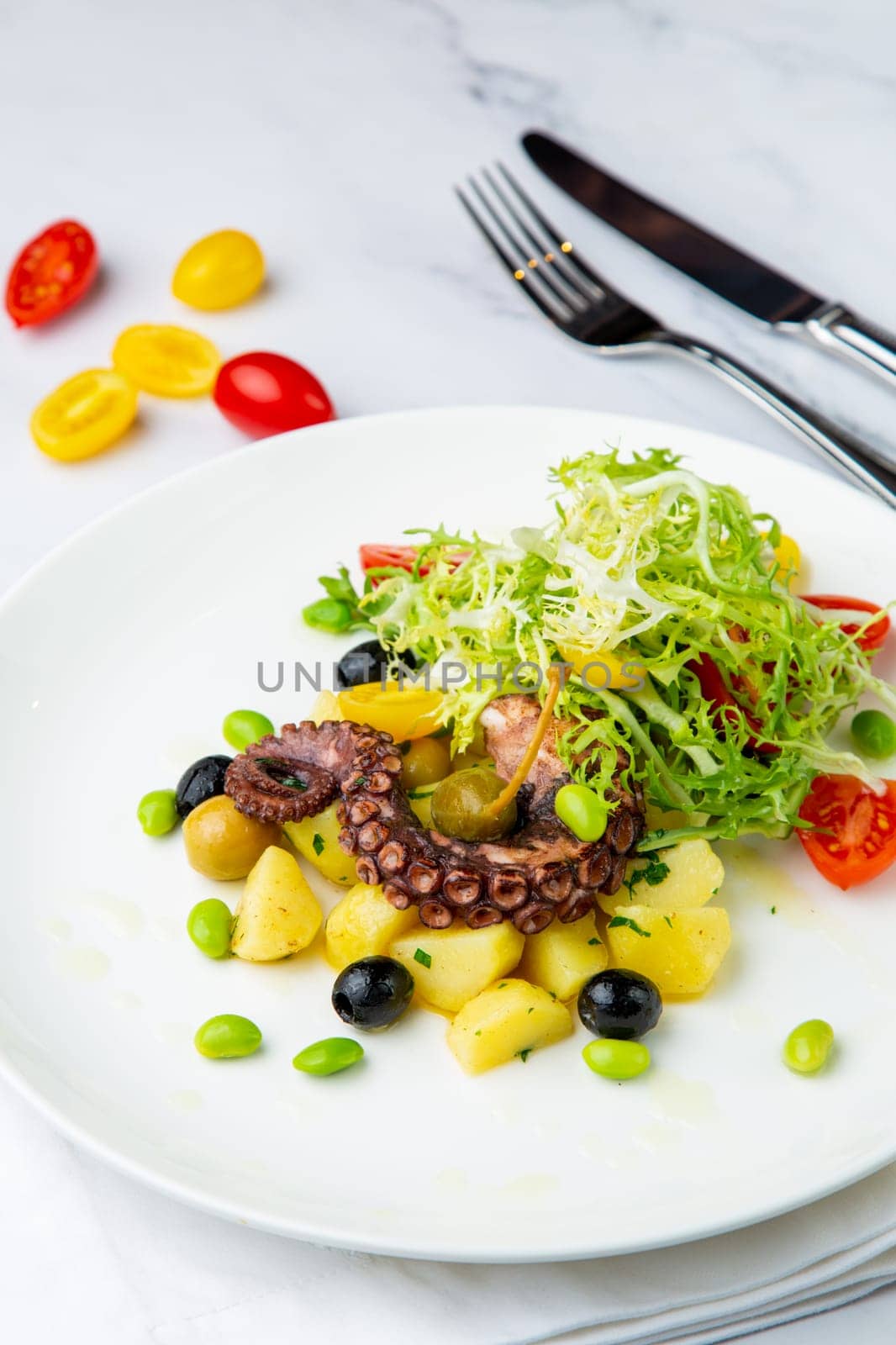 salad with olives, herbs, cherry tomatoes, potatoes and octopus tentacles
