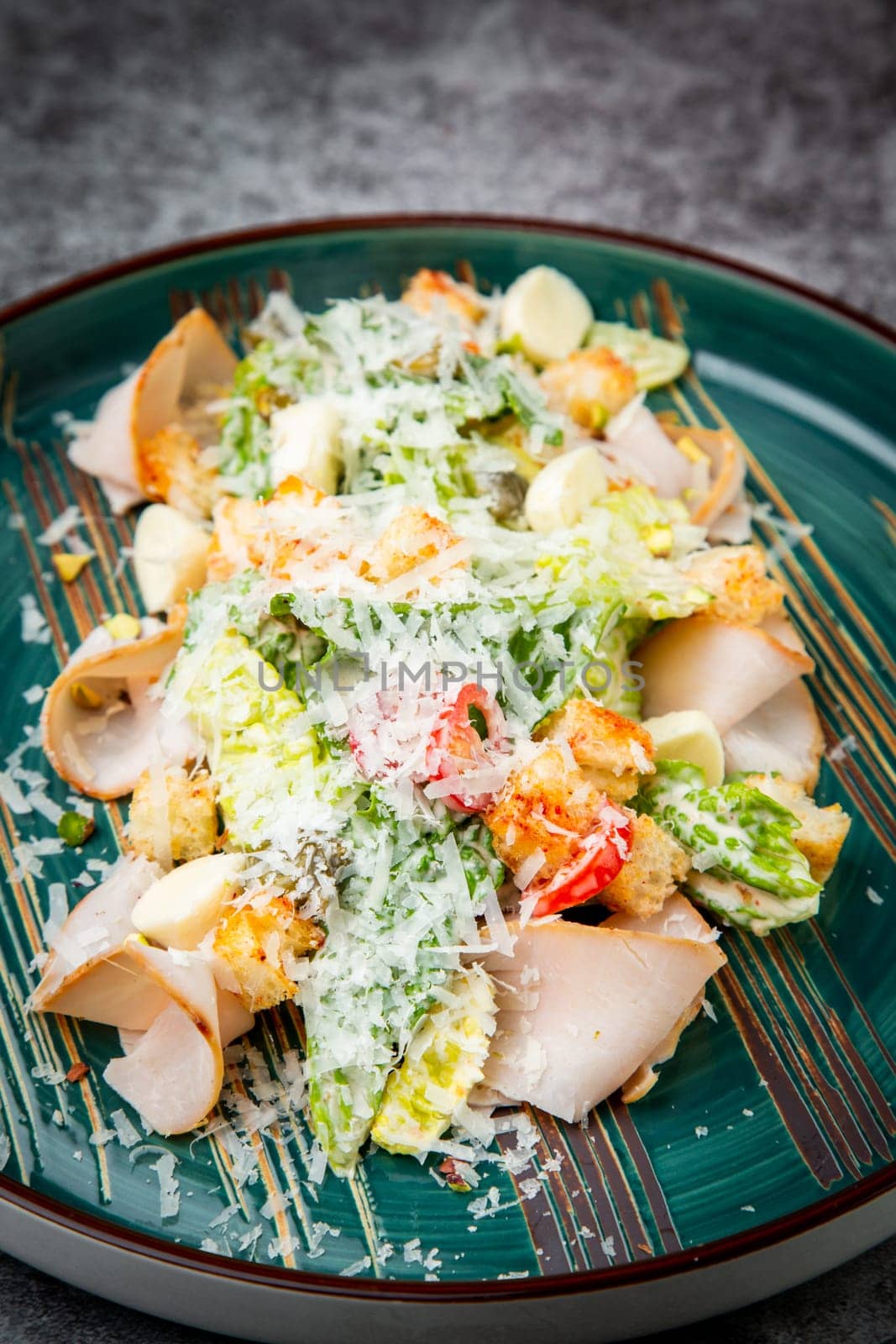 side view of caesar salad with cheese on a blue plate by tewolf