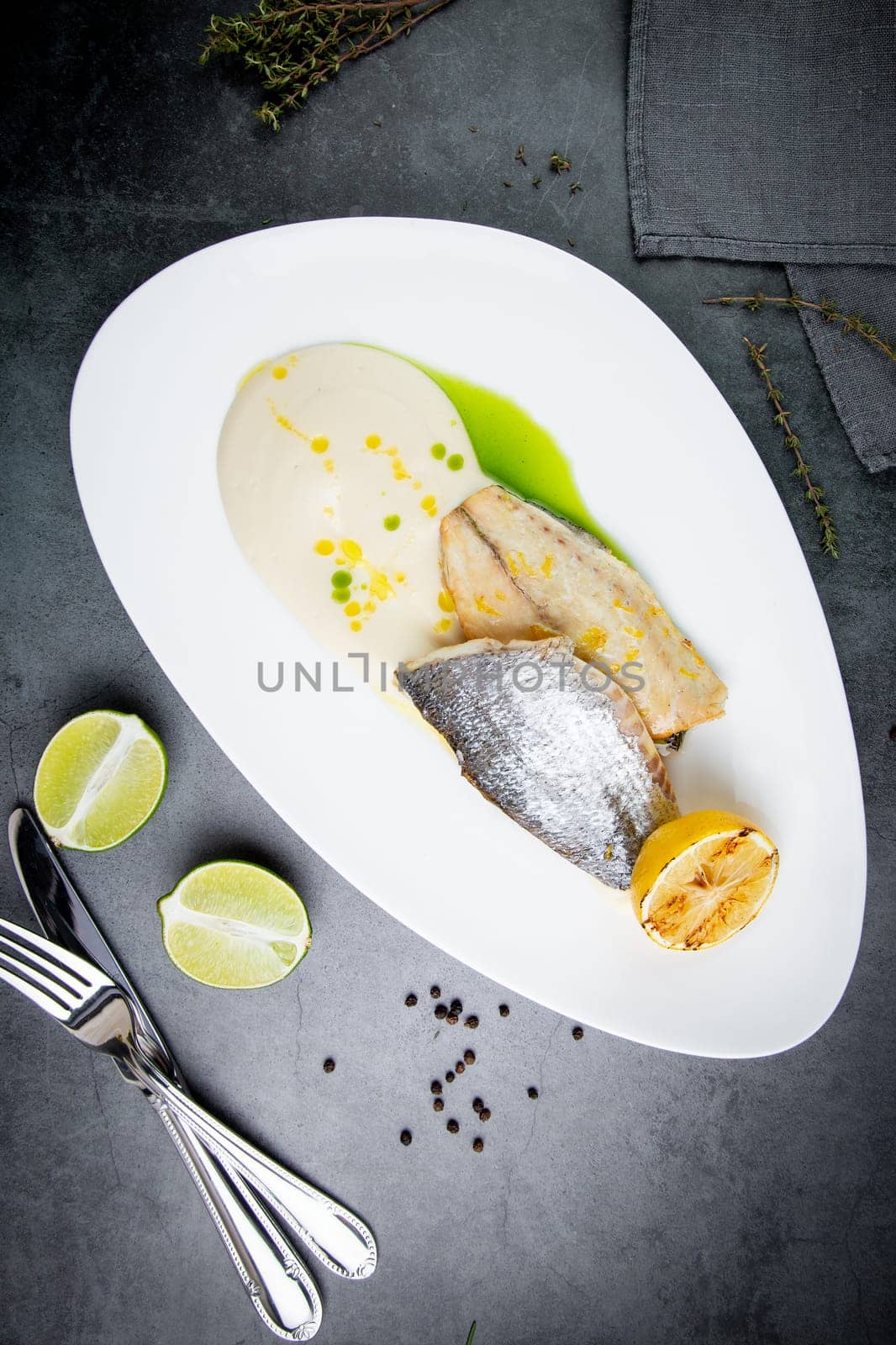 pieces of fried fish with sauce and fried lemon on a white plate top view by tewolf