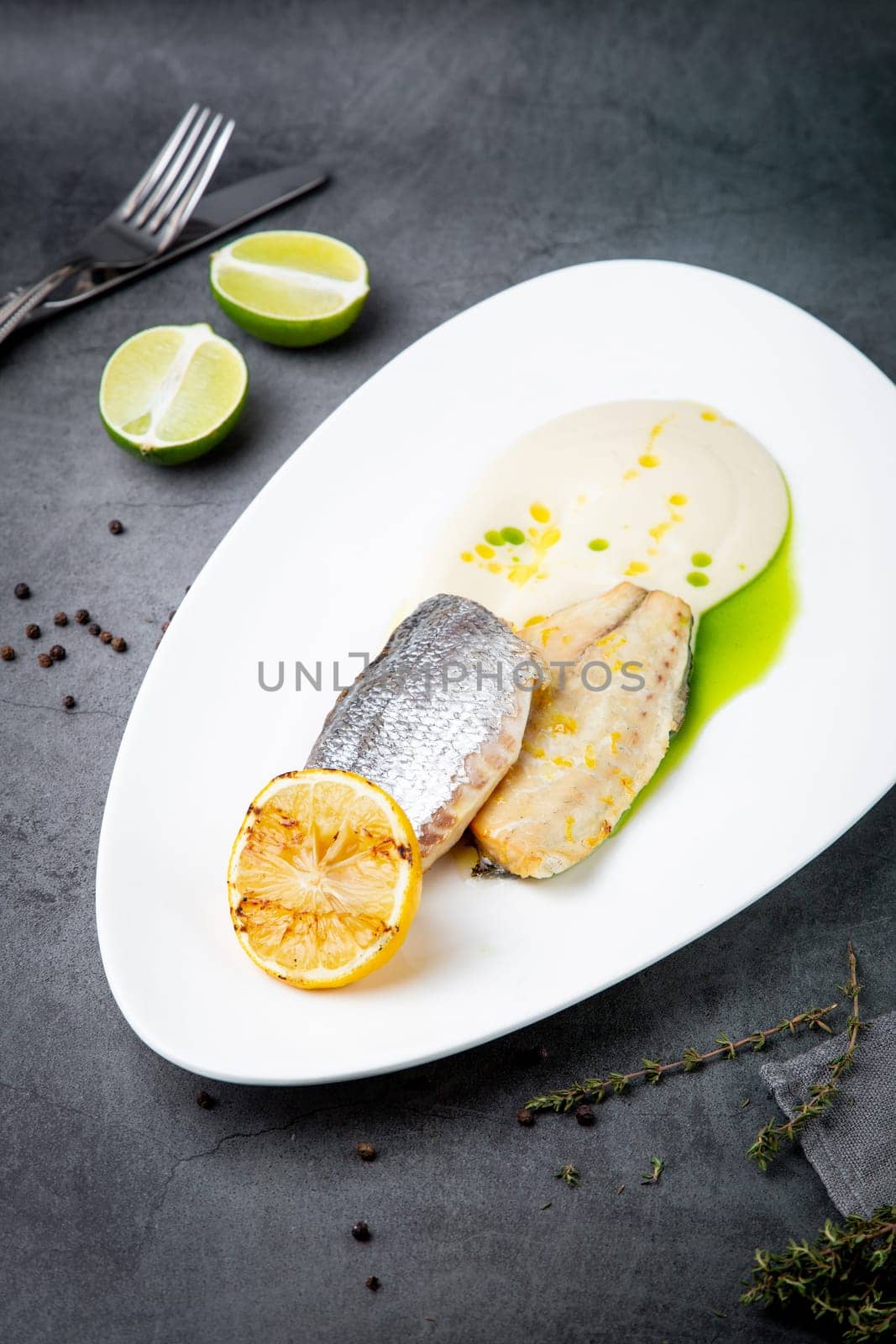 pieces of fried fish with sauce and fried lemon on a white plate side view by tewolf