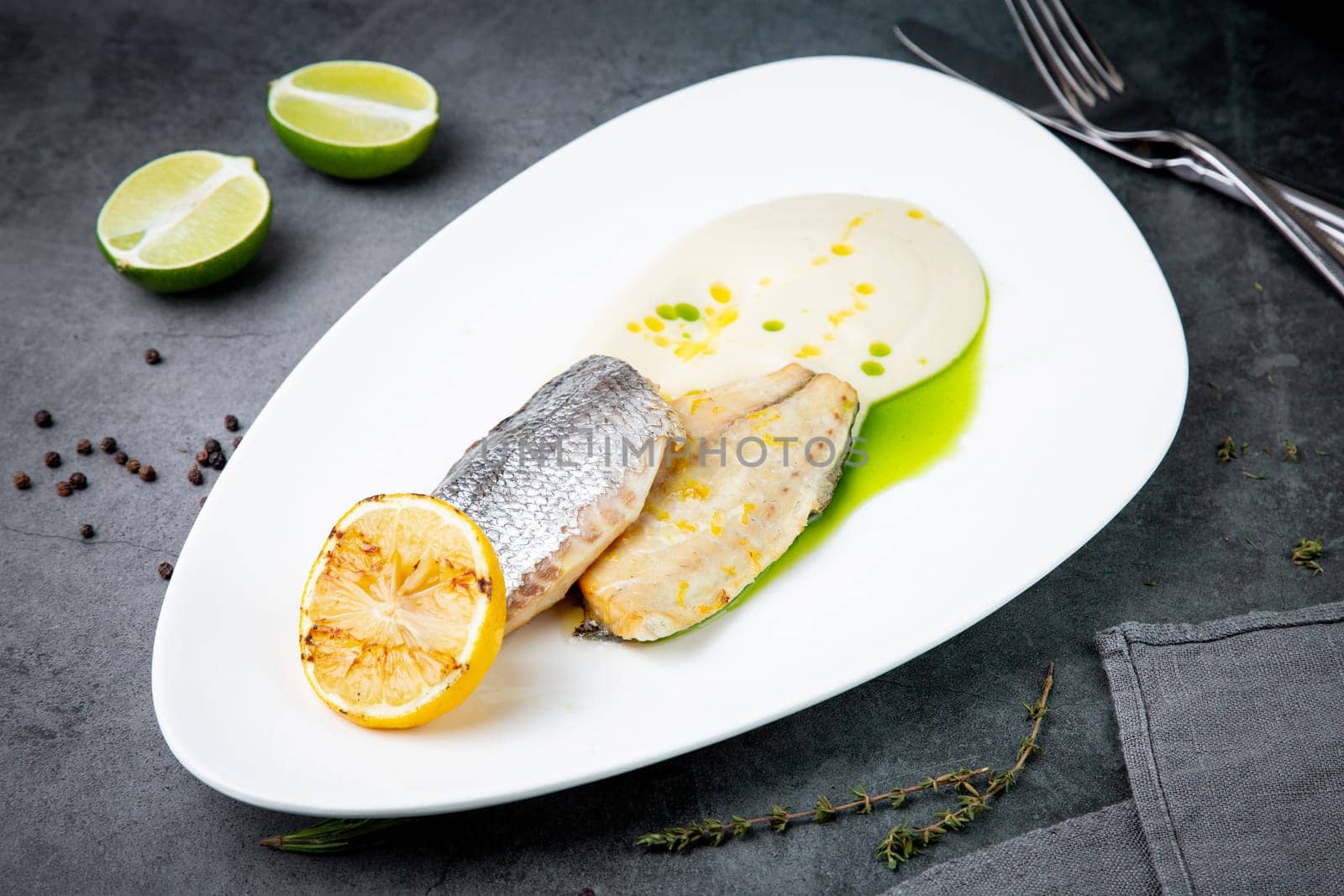 pieces of fried fish with sauce and fried lemon on a white plate side view by tewolf