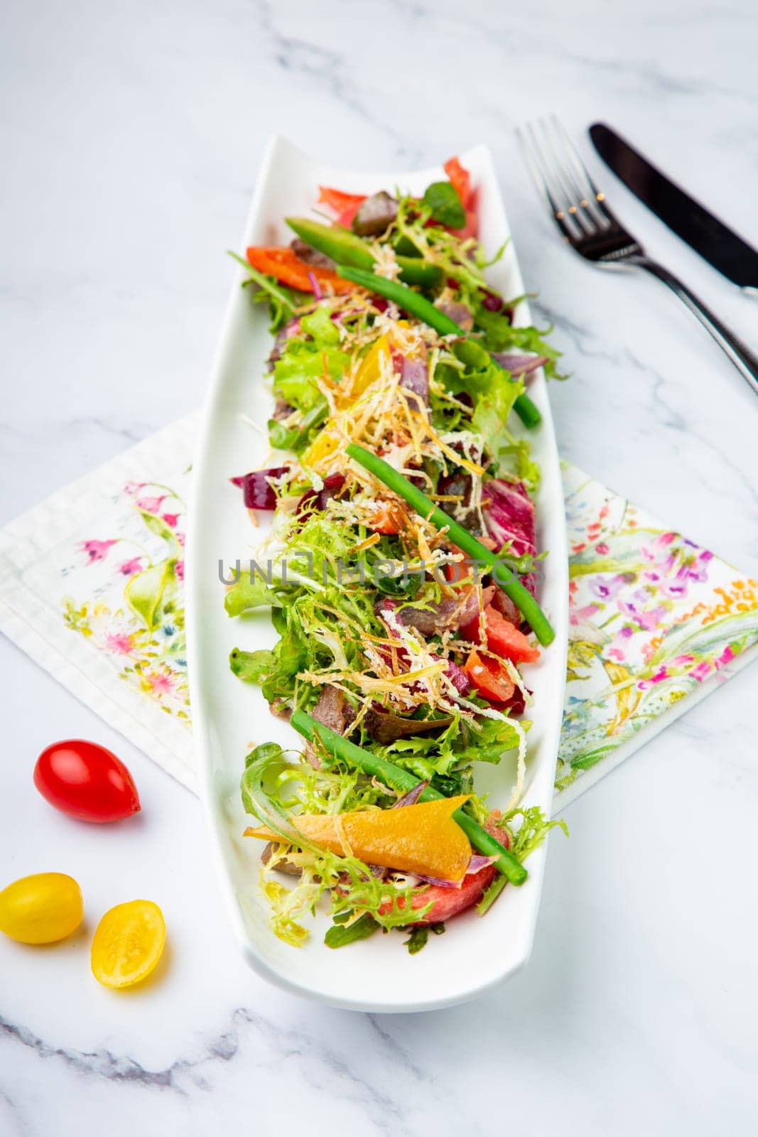 green salad with cherry tomatoes on a white oblong plate