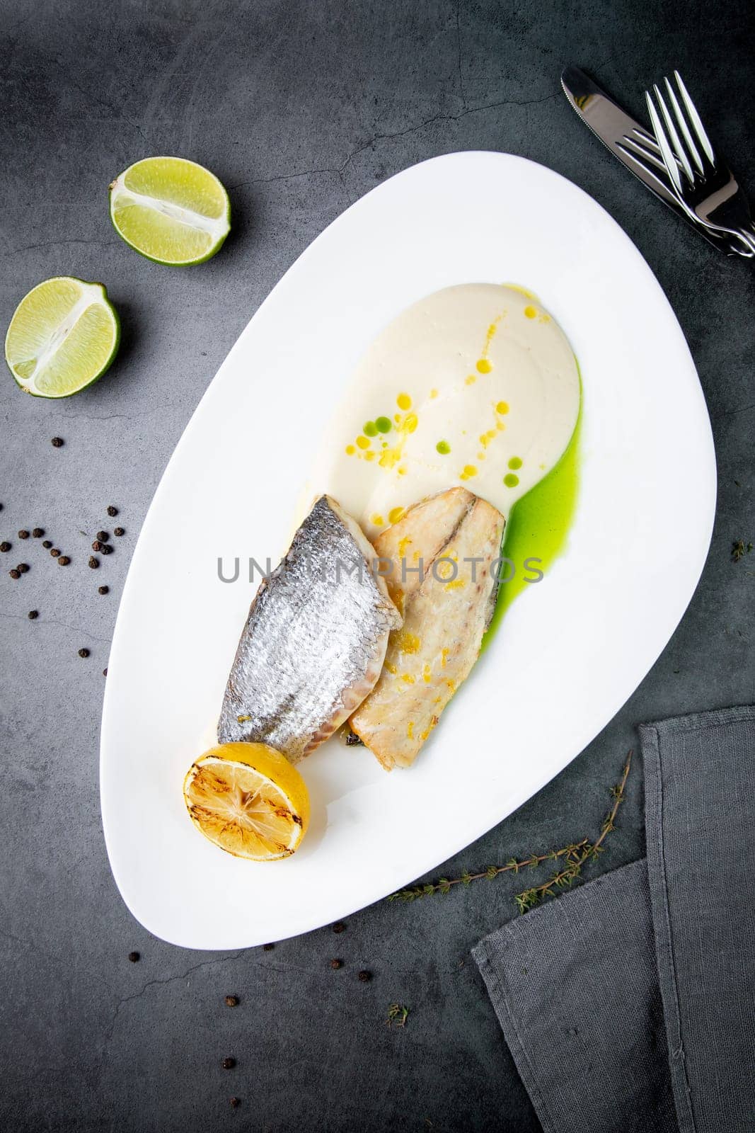 pieces of fried fish with sauce and fried lemon on a white plate top view by tewolf