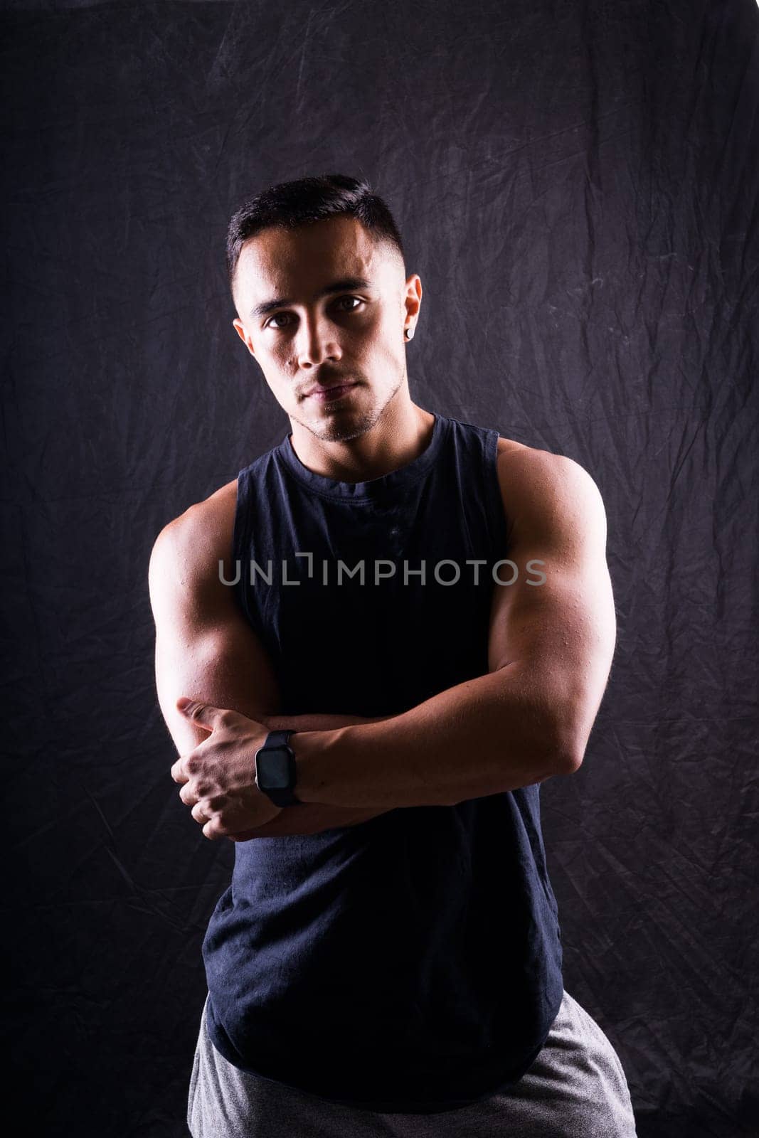 Confident, attractive shirtless muscular young man topless in a studio