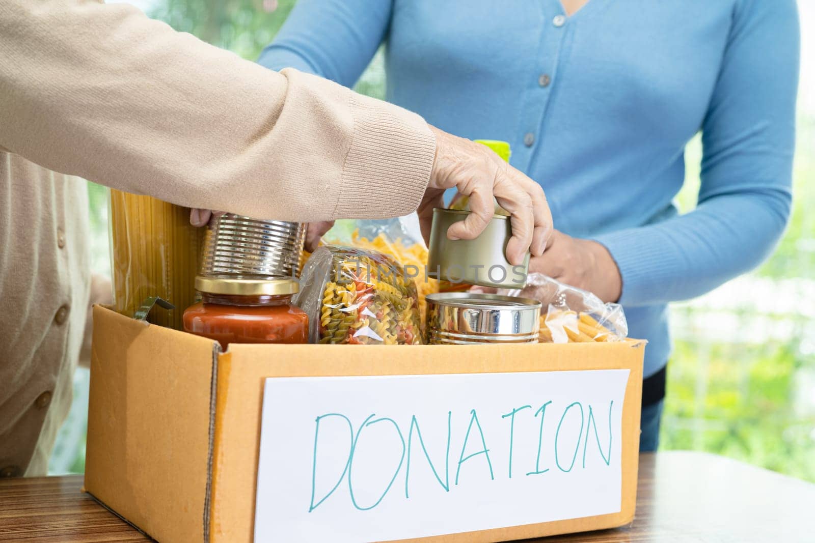 Volunteers putting various dry food in donation box for help people.