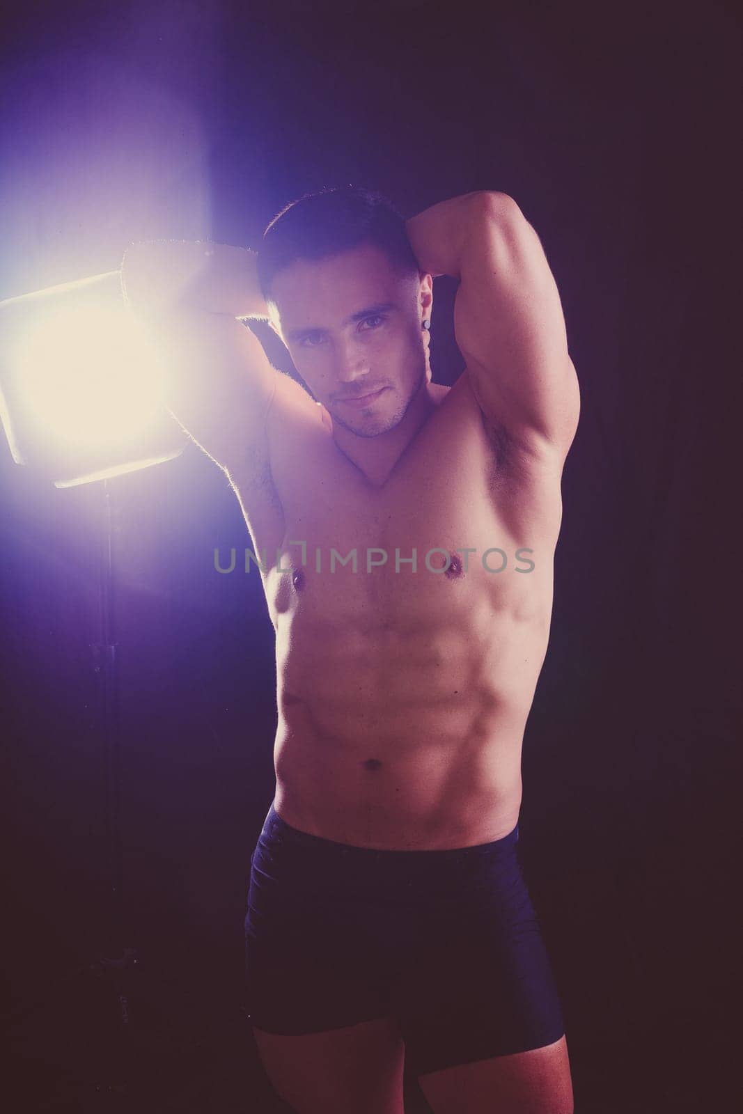 Confident, attractive shirtless muscular young man topless in studio by Zelenin