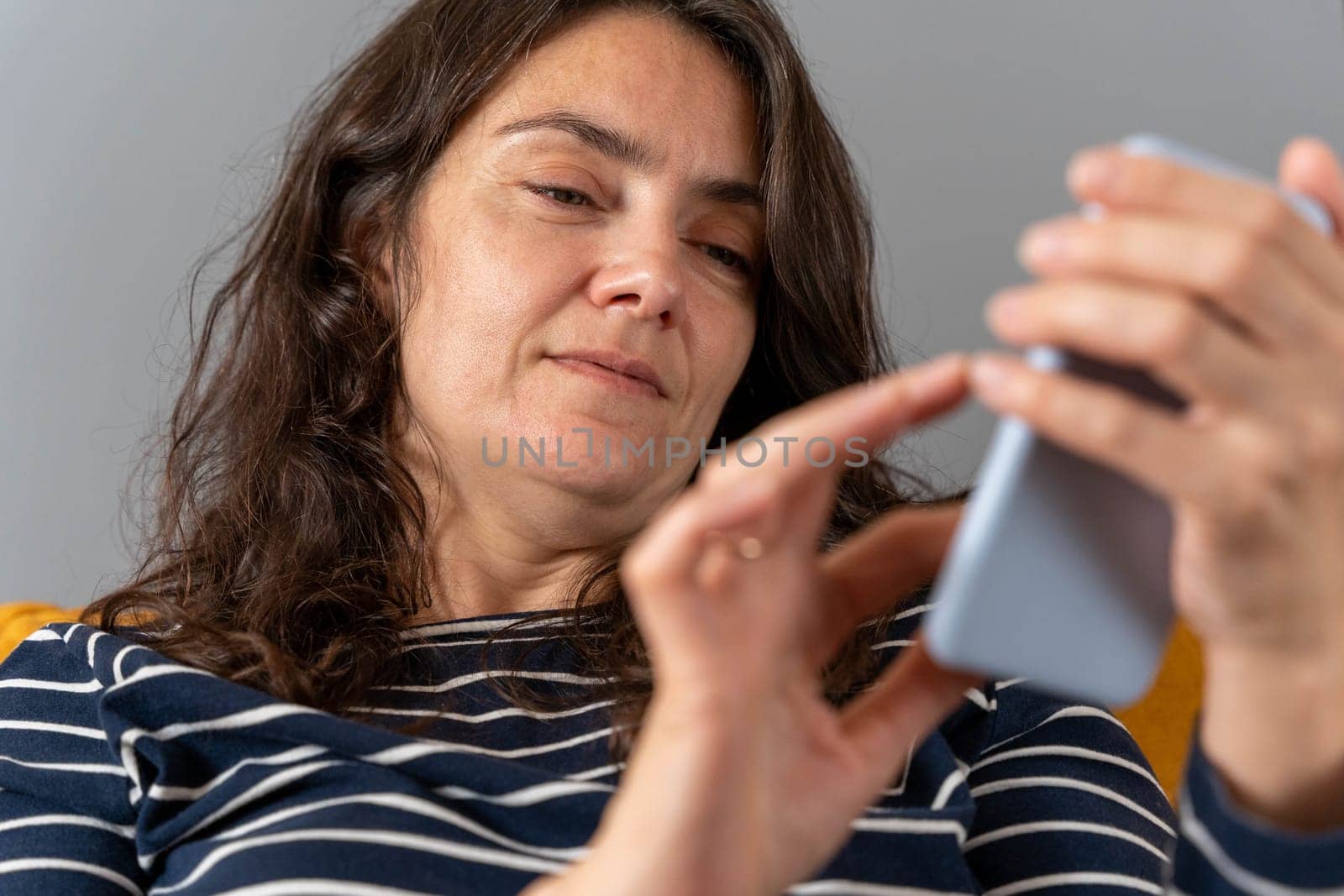 a relaxed woman on a home sofa with her smartphone on a social network. active life position. The girl is typing a text message. view from above