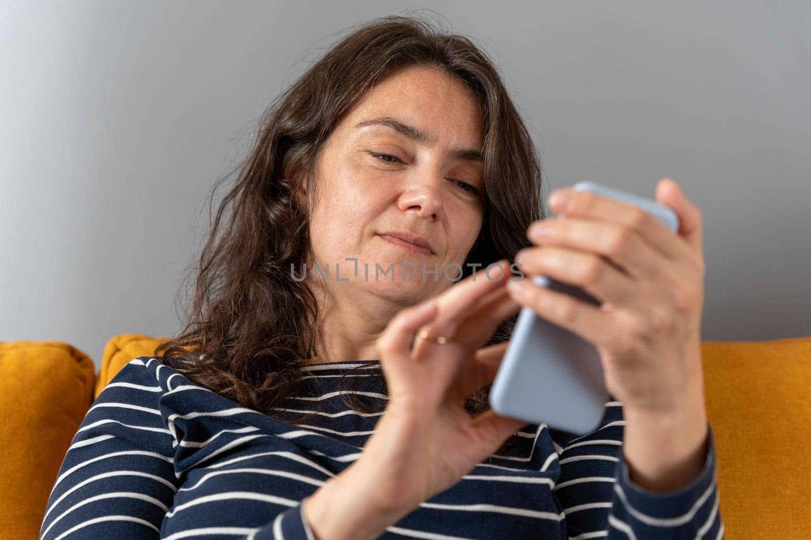 relaxed woman on a home sofa with her smartphone on a social network by audiznam2609