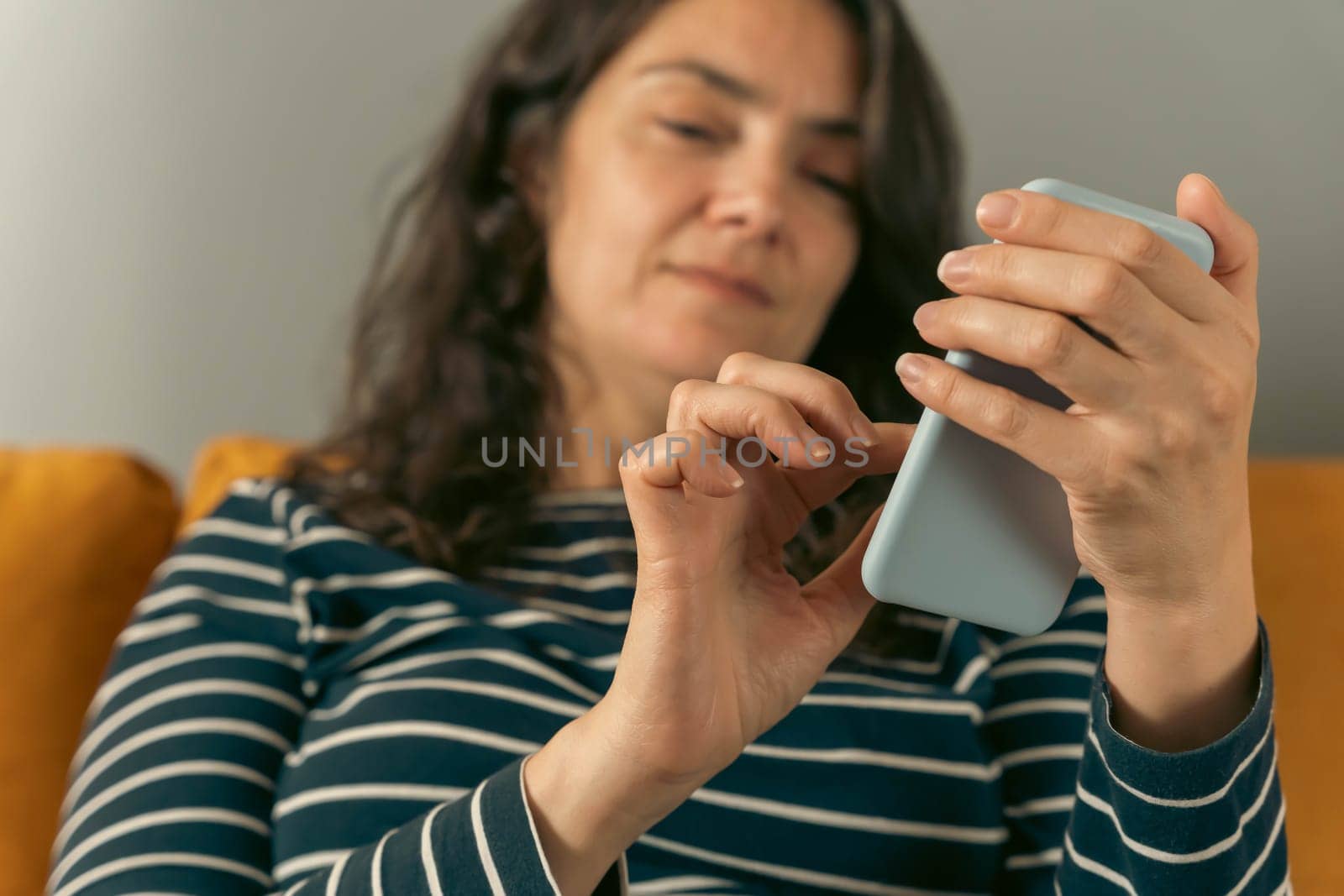 relaxed woman on a home sofa with her smartphone on a social network by audiznam2609