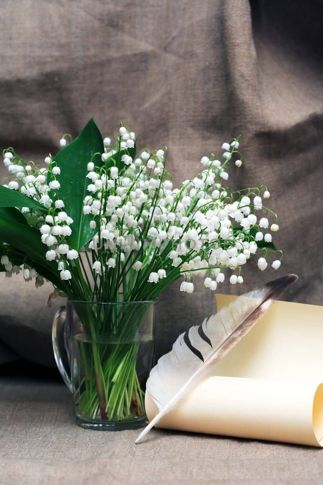 Still life with open book and quill pen near posy of white lilies