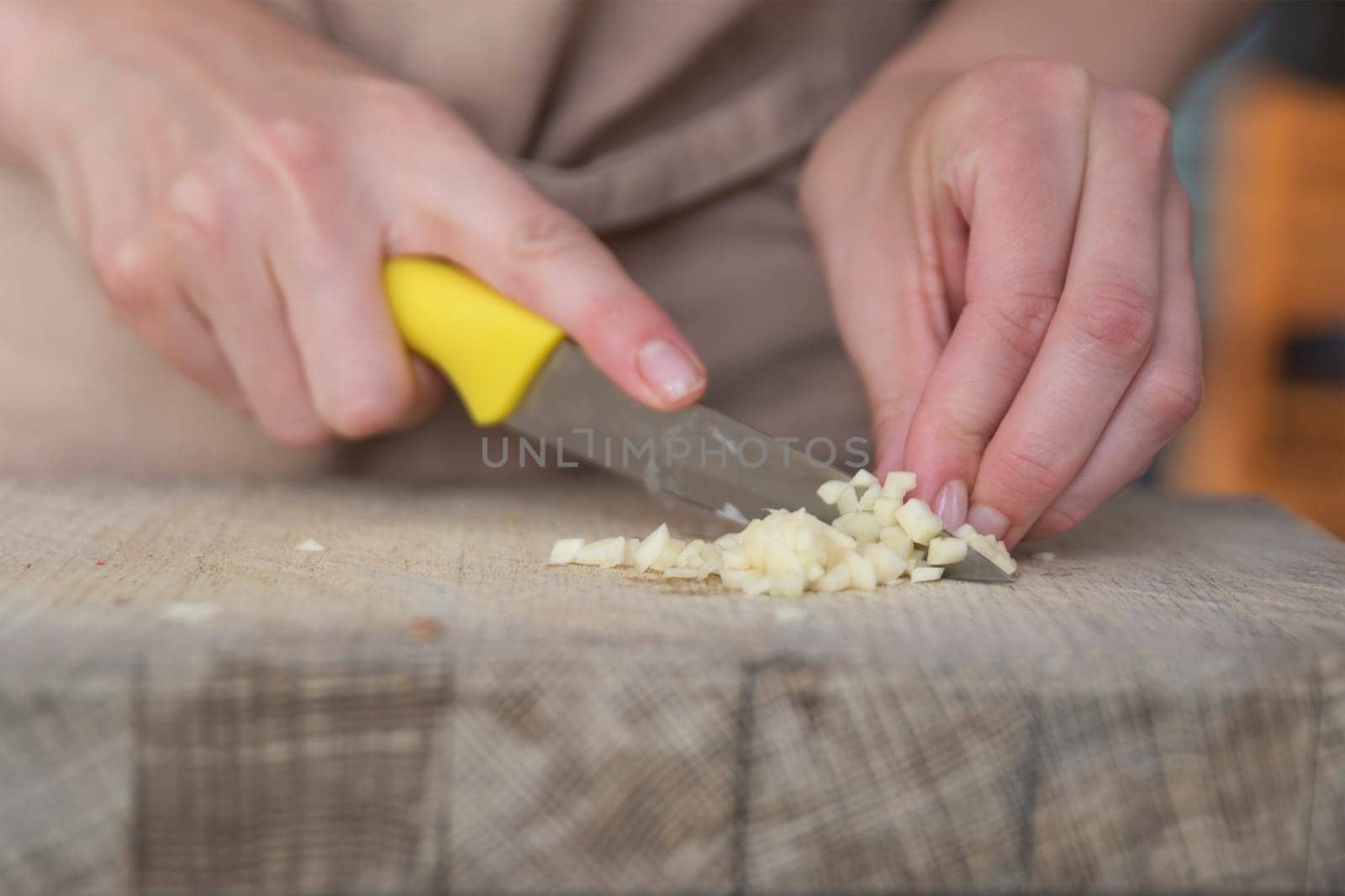 A woman cuts garlic with a knife close-up. Cutting garlic for salad or as an aromatic spice for meat. by SERSOL