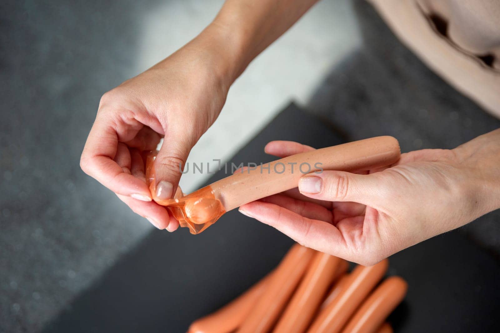 Close-up of a woman removing the skin from a sausage. Preparation for decorating the table for guests. High quality photo