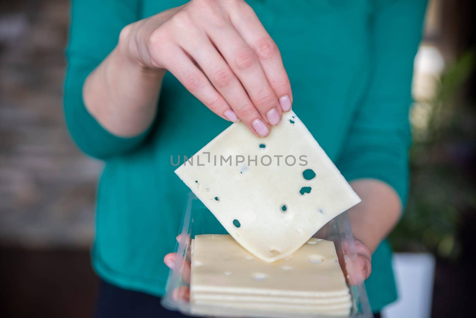 A woman's hand takes a piece of cheese from a pack close-up. Preparing for Cheese Lovers Day. High quality photo