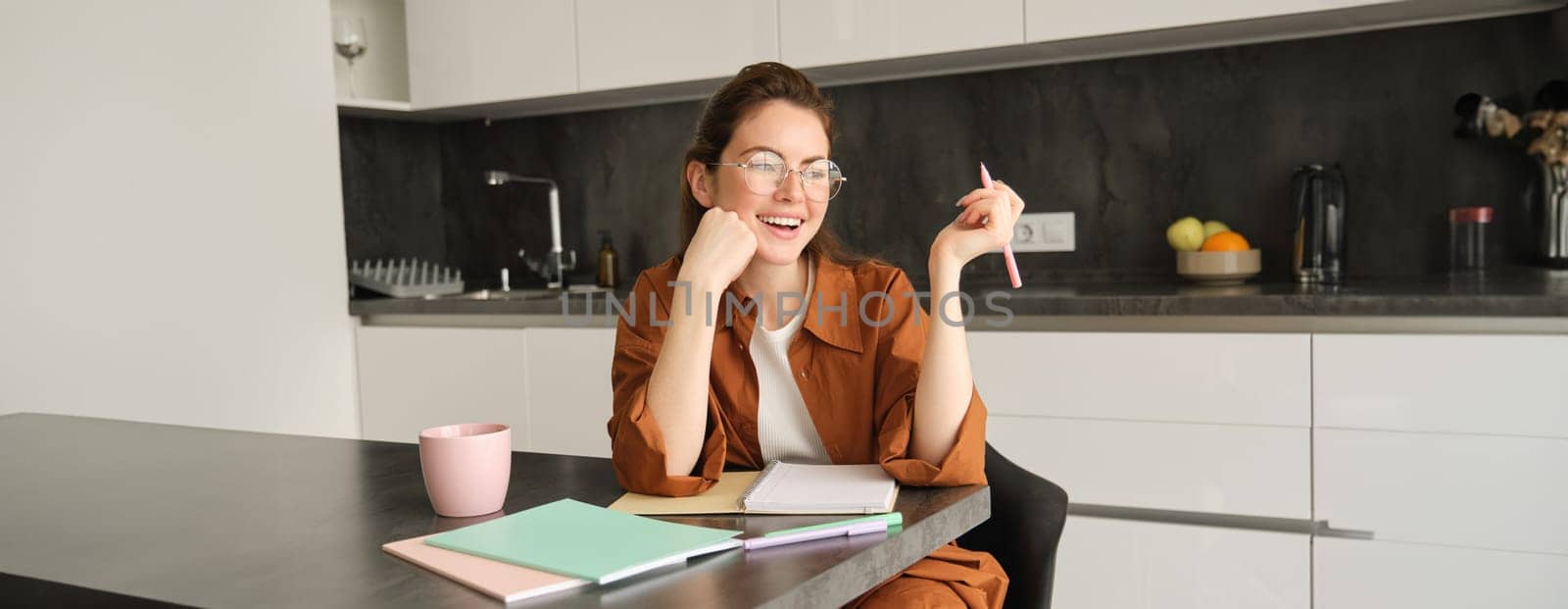 Portrait of young beautiful woman with pen, writing, student studying at home, doing homework, making notes, using her planner.