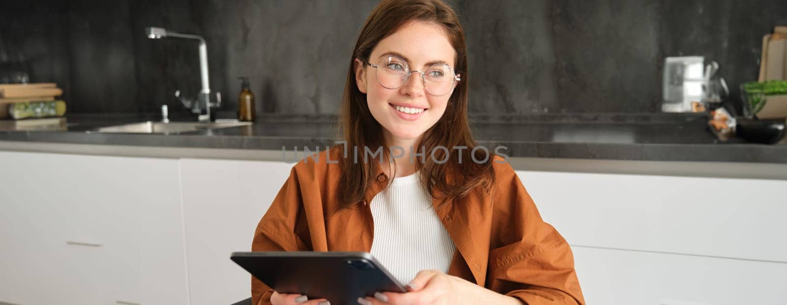 Portrait of beautiful young brunette woman, holding digital tablet, reading with glasses, smiling, surfing the net using gadget.