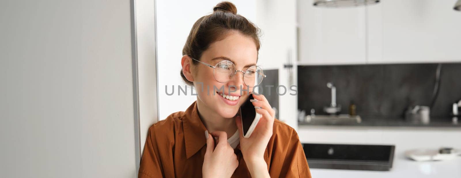 Portrait of happy smiling young woman at home, talking on mobile phone, calling friend and having nice conversation, answer telephone.