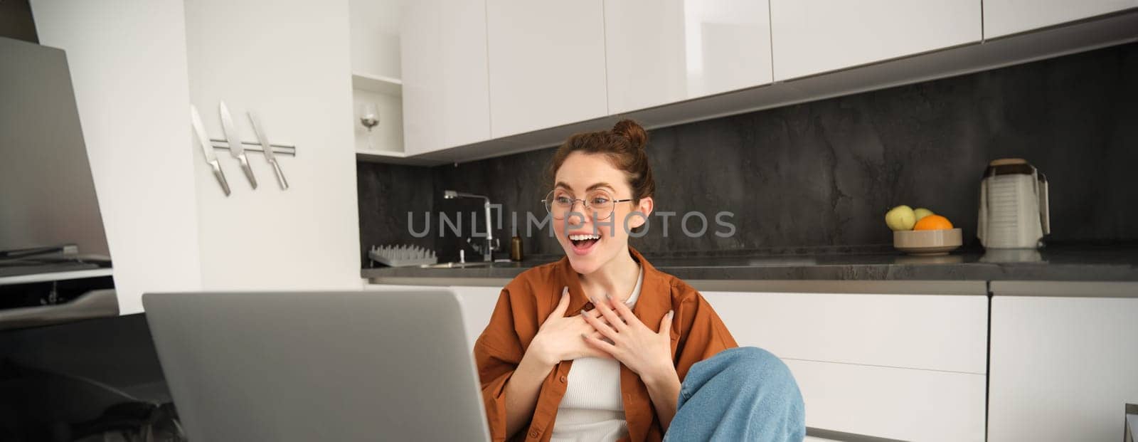 Portrait of young woman working from home, sitting at home with laptop, talking with friend on computer, online chatting, connects to video conversation.