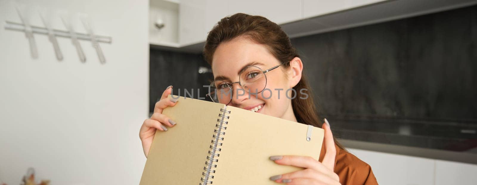 Close up portrait of young woman smiling, holding notebook, showing her planner.