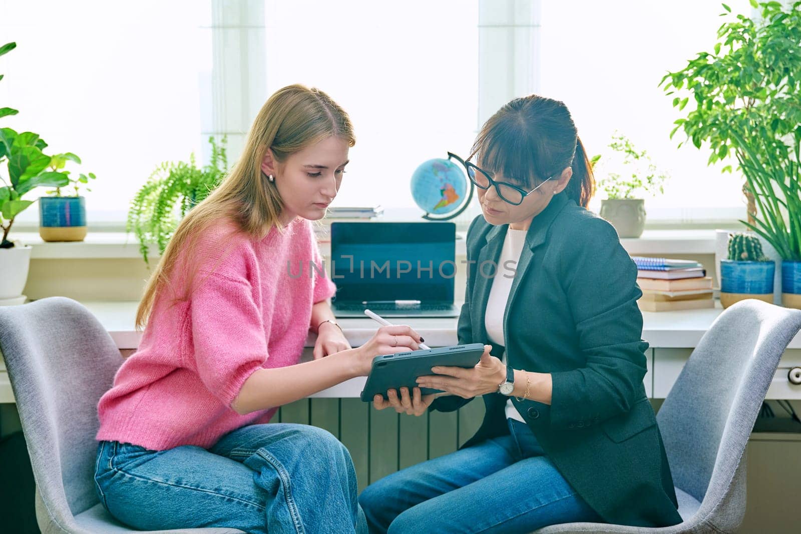 Counselor talking with teenage girl, using digital tablet for work by VH-studio