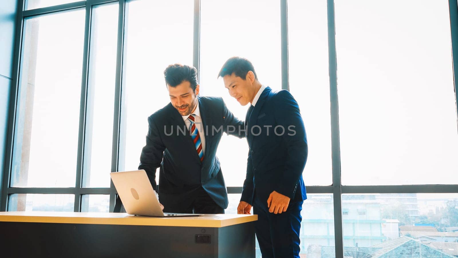 Two business people talk project strategy at office meeting room. Businessman discuss project planning with colleague at modern workplace while having conversation and advice on financial report. Jivy