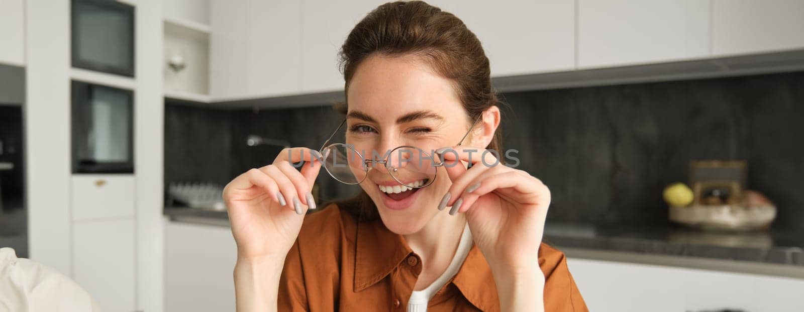 Close up portrait of beautiful brunette woman at home, smiling, wearing her glasses and laughing.