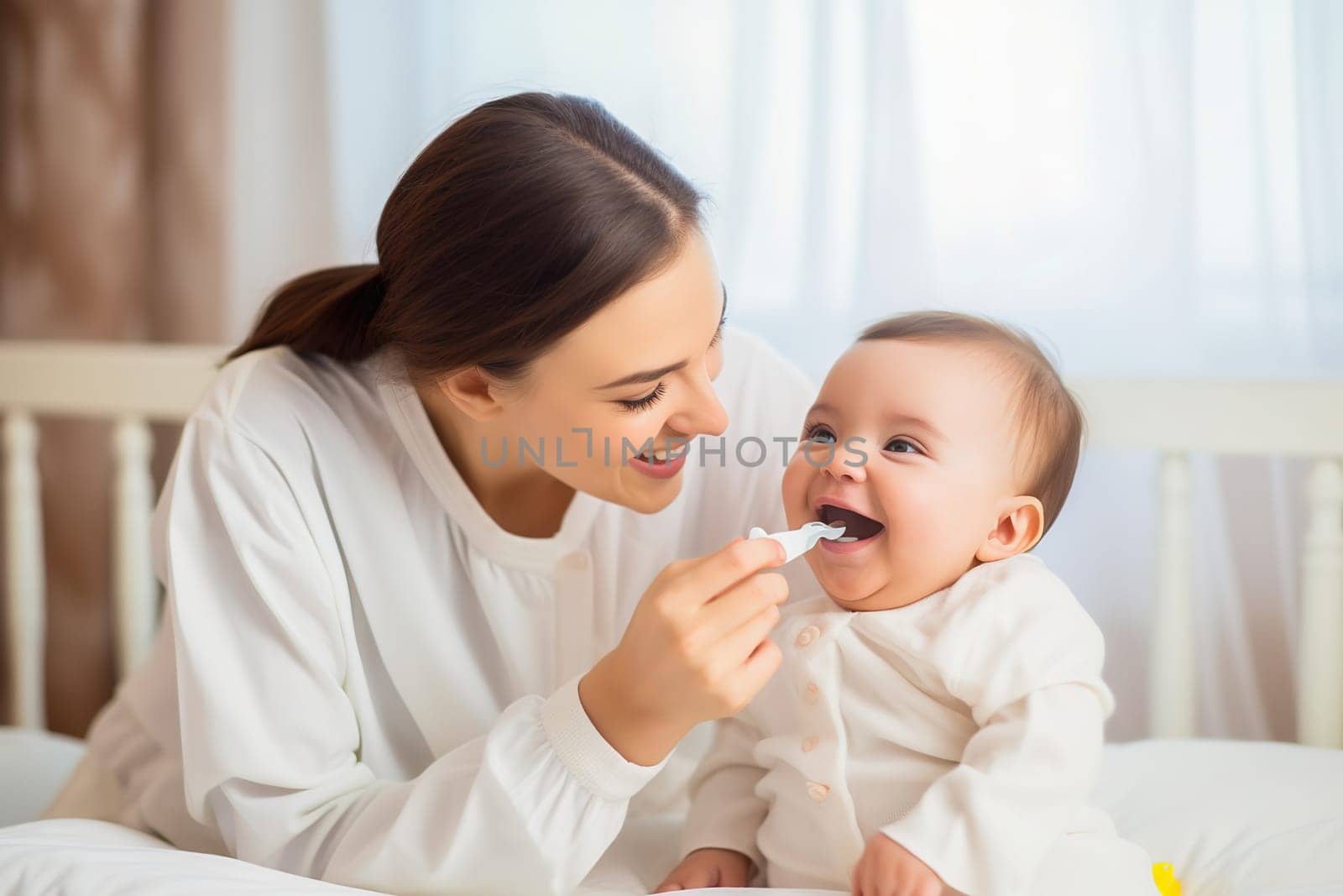 A happy mom feeds her baby from a spoon. by Yurich32