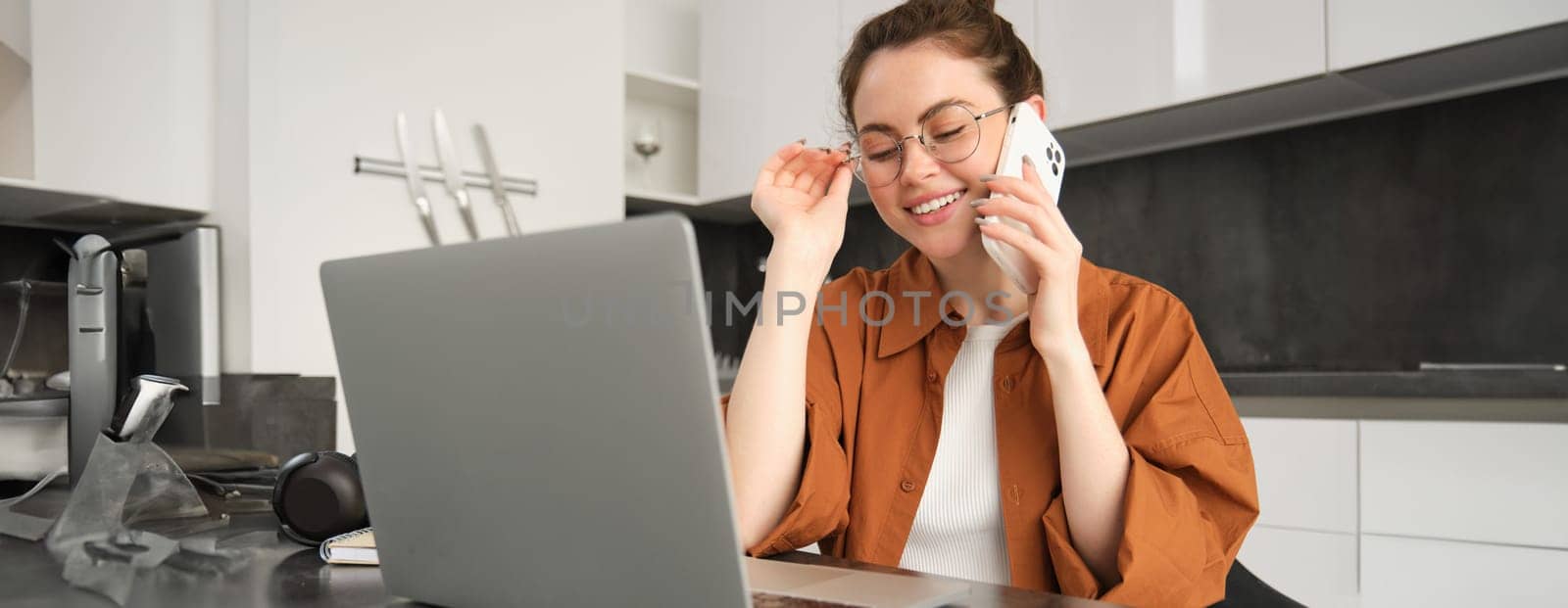 Portrait of young woman at home, doing online shopping. Businesswoman has own start-up making a phone call, has conversation with client, saleswoman trading online, using laptop.