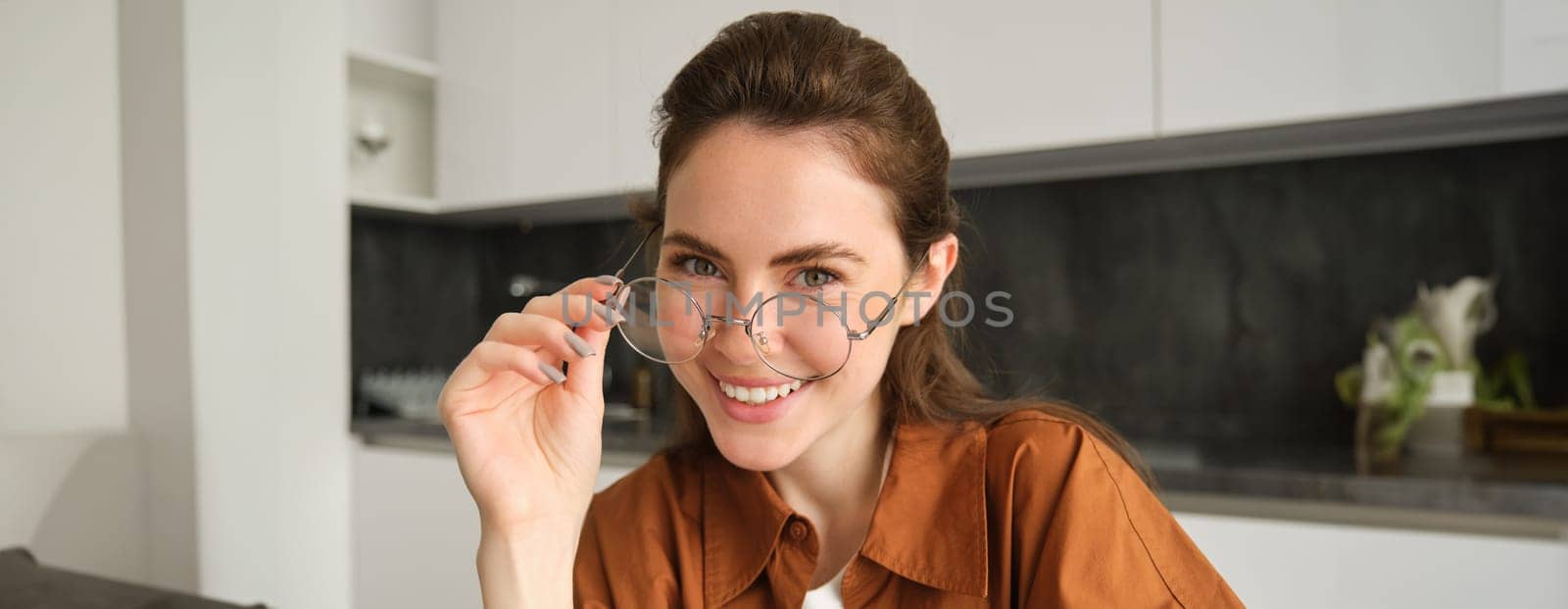 Close up portrait of beautiful brunette woman at home, smiling, wearing her glasses and laughing.