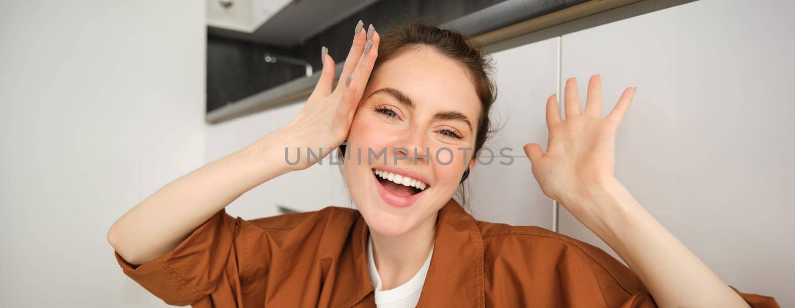 Close up portrait, face of happy woman, enjoying listening to music, wearing wireless headphones, laughing and smiling.