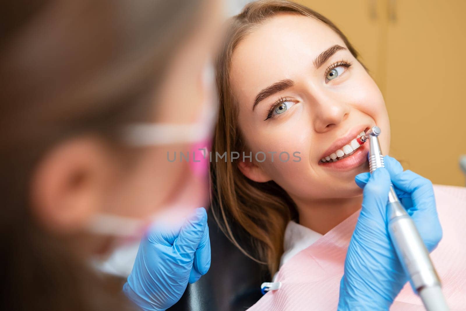 Woman patient sitting in a medical chair during teeth grinding procedure. Teeth care concept