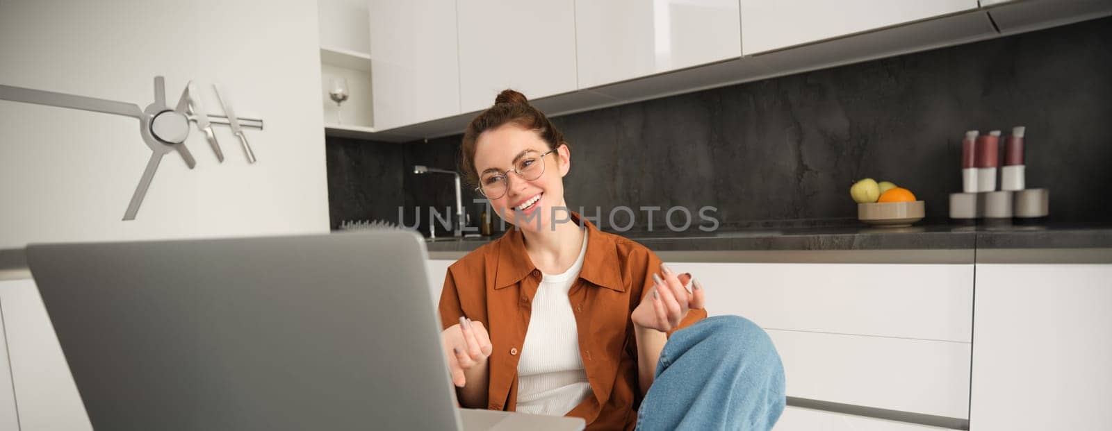 Portrait of young woman working from home, sitting at home with laptop, talking with friend on computer, online chatting, connects to video conversation by Benzoix