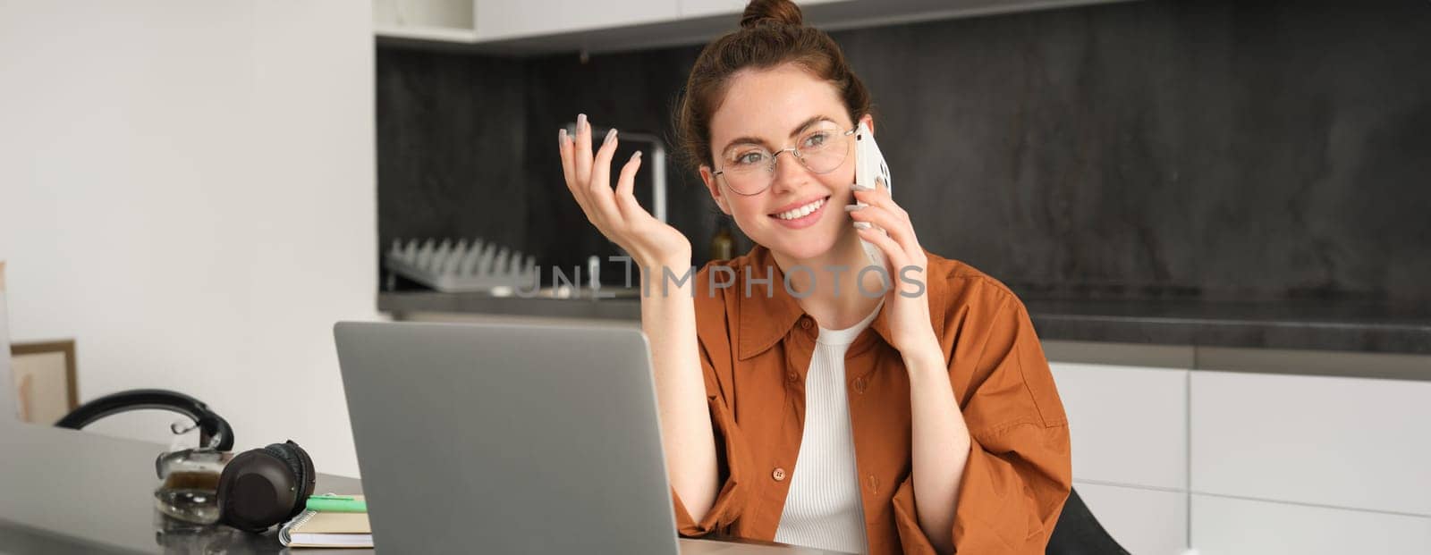 Portrait of young woman at home, doing online shopping. Businesswoman has own start-up making a phone call, has conversation with client, saleswoman trading online, using laptop.