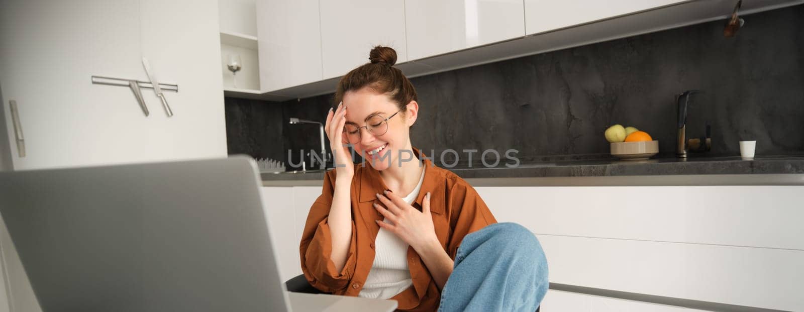 Work from home, remote job concept. Young woman sitting in kitchen, using laptop, joins video chat conversation, give online lessons, talking to client on computer.