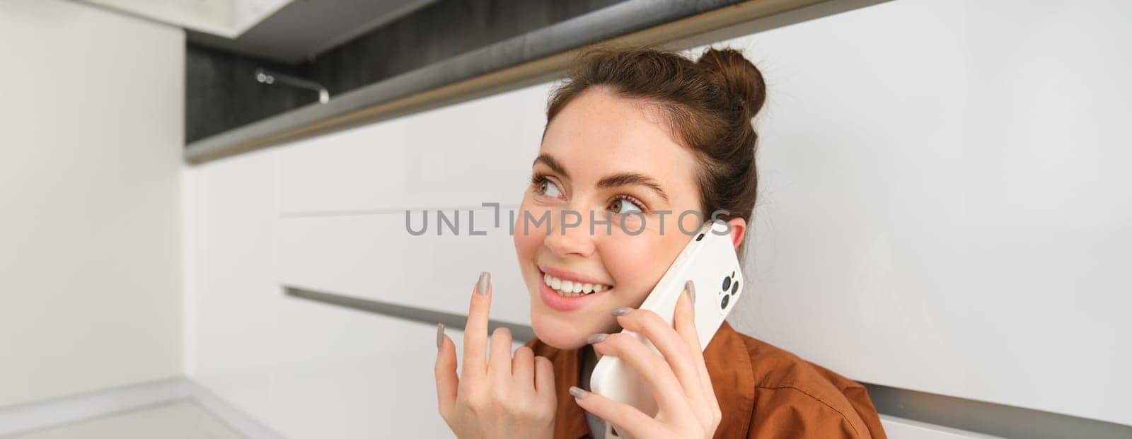Close up of beautiful female model talks on phone, making a call, smiles and looks happy.